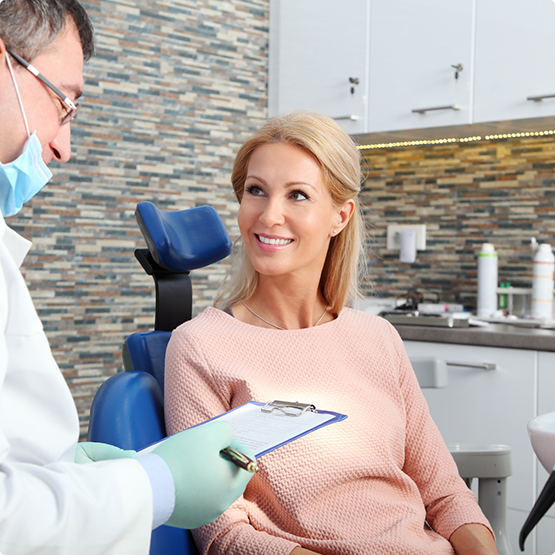 Female patient in pink shirt smiling at dentist