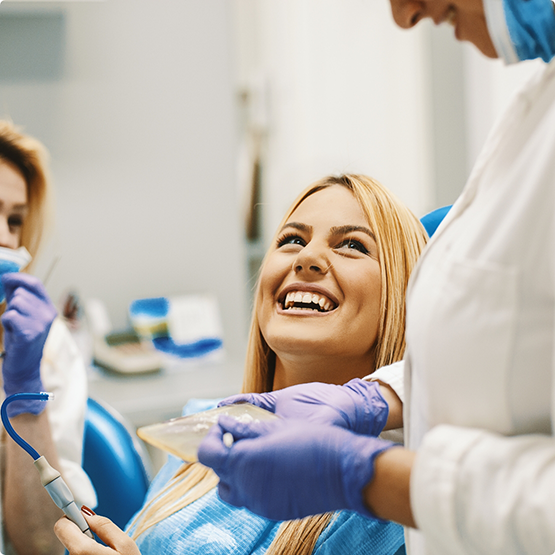 Blonde female patient looking up at dentist and smiling