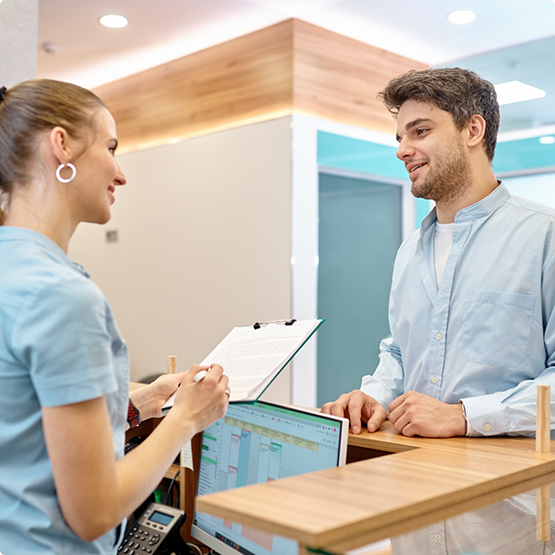 Dental team member with clipboard talking to patient