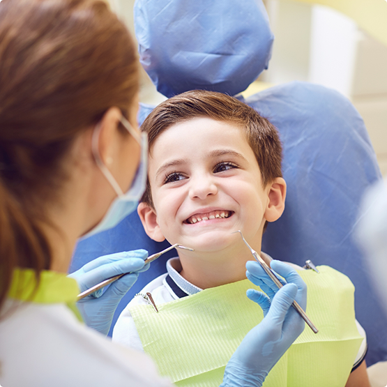 Little boy in dental chair smiling up at children's dentist in Phoenix