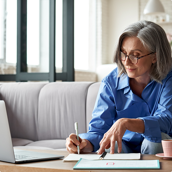 Woman sitting at laptop looking at some forms