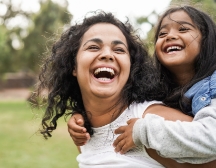 Woman giving little girl a piggyback ride