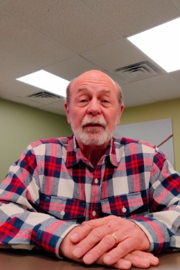 Man in patterned shirt sitting at table