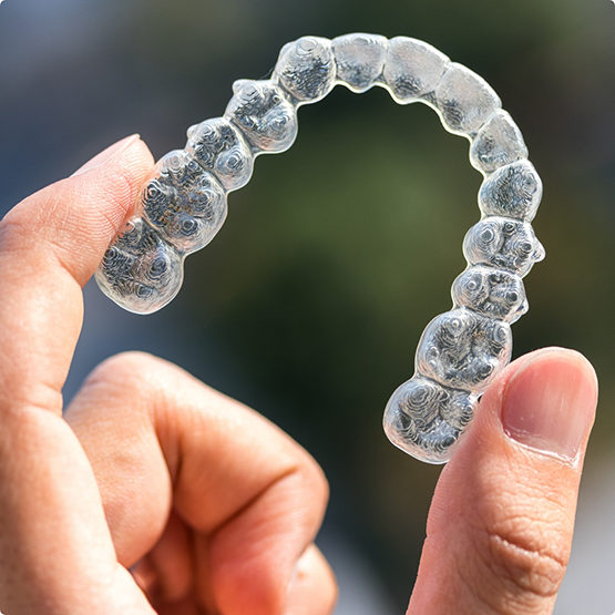 Close up of hand holding Invisalign clear aligner