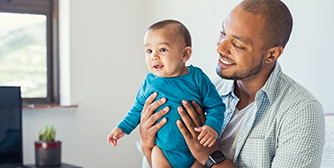 Smiling man holding a baby in a blue shirt