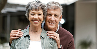 Senior man and woman standing outside and smiling