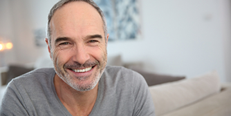 Man with grey shirt smiling in living room