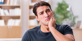 Man rubbing jaw in pain looking concerned