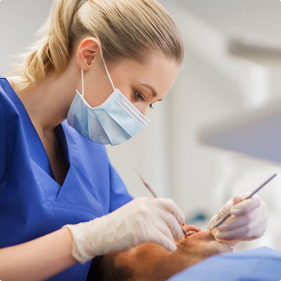 Dentist with mask performing a dental cleaning