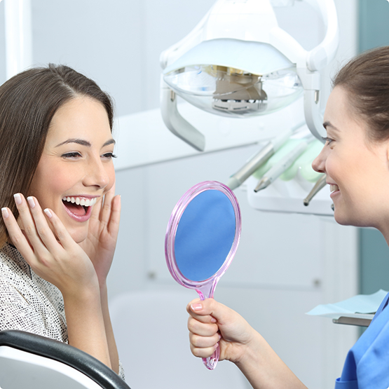 Dentist holding up mirror for smiling patient