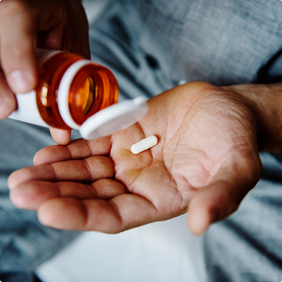 Close up of person holding pill and bottle