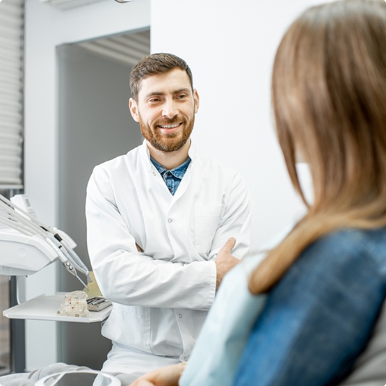 Bearded dentist smiling and speaking to a patient